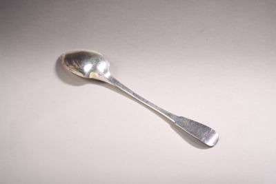 une cuillère en argent avec un manche de cuillère sur une surface blanche