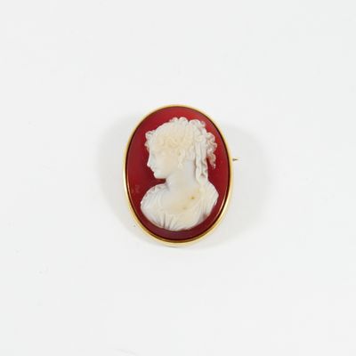 un gros plan sur une broche rouge et blanche représentant le profil d'une femme