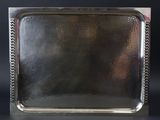 un plateau en argent muni d'une poignée, posé sur une table noire