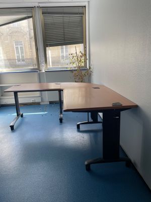 un bureau dans un coin d'une pièce, avec une fenêtre en arrière-plan