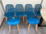 quatre chaises bleues placées les unes à côté des autres sur un plancher en bois