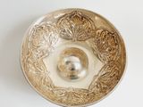 a silver bowl on a white surface with a silver ball in it