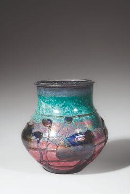 a colorful vase with birds on it sitting on a table