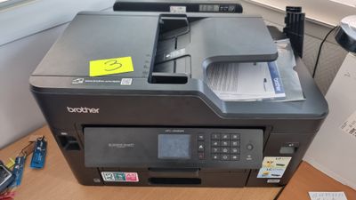 a printer that is sitting on a desk in front of a window