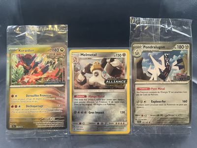 trois cartes Pokémon dans des pochettes en plastique, posées sur une table