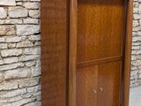 an image of a tall wooden cabinet against a brick wall