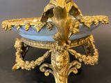 a gold and blue bowl on a stand on a black surface