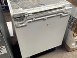 a white dishwasher sitting next to a refrigerator in a warehouse
