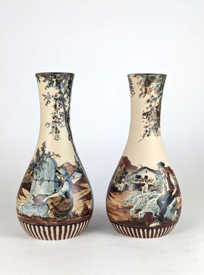 pair of vases with asian scenes on them sitting on a white surface
