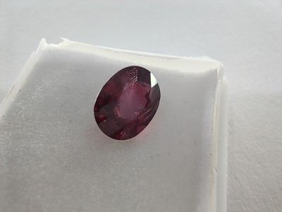 a close up of a red ruby stone on a white surface