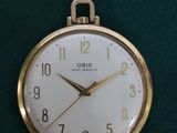 une montre de poche en or posée sur un tissu vert
