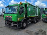 two green garbage trucks parked in a parking lot next to each other