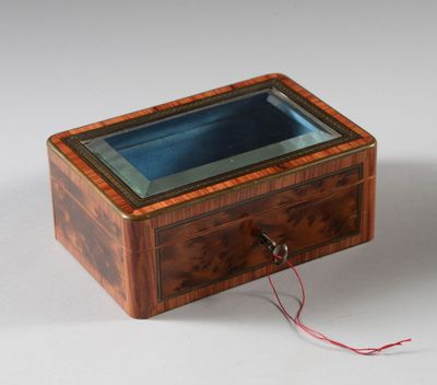 une vieille boîte en bois avec un couvercle en verre, posée sur une surface blanche