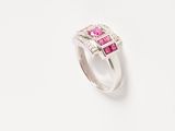 a close up of a pink and white diamond ring on a white surface