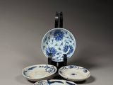 four blue and white plates and a bowl on a gray surface