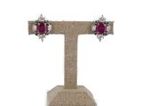 une paire de boucles d'oreilles en rubis et diamants, posées sur un présentoir