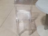 clear acrylic stacking chairs and a table in a room