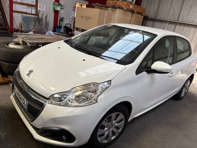 une voiture blanche garée dans un garage, à côté d'un tas de pneus