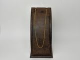 présentoir à bijoux en bois avec une chaîne dorée sur fond blanc