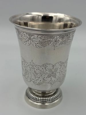 a close up of a silver cup on a white surface