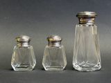 trois salières et poivrières en verre posées sur une table