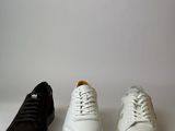 three pairs of white and black sneakers are lined up on a white surface