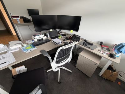un bureau d'ordinateur avec deux écrans et une chaise dans un coin