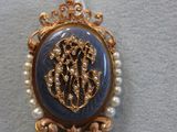 une photo d'une broche bleue et dorée ornée de perles, montée sur un collier