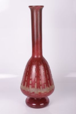 un vase rouge posé sur une surface blanche