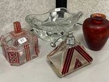 trois récipients en verre posés sur une étagère en verre, à côté d'un vase rouge