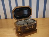 a small wooden box with two cups in it on a table