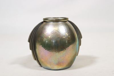 un vase argenté muni d'une poignée en métal, posé sur une surface blanche