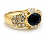 a close up of a gold ring with a sapphire and diamonds