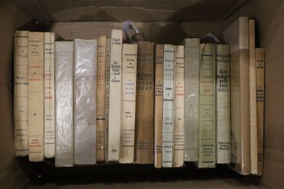 une boîte pleine de vieux livres posée sur le sol