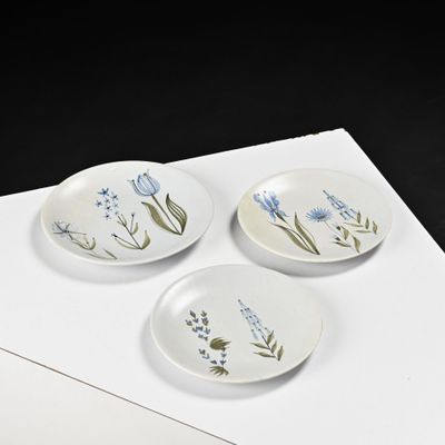 three plates with flowers painted on them sitting on a piece of paper