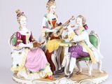 trois figurines représentant des personnes assises autour d'une table et jouant d'instruments de musique