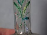 a hand holding a glass vase with flowers painted on it