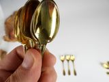 a person holding a gold spoon and fork in their hand