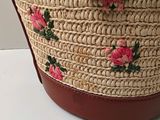 a straw bag with pink flowers on it sitting on a table