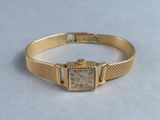 an image of a gold wrist watch with a square face