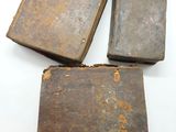 trois vieux livres sont posés sur une surface blanche