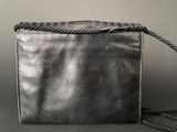 black leather purse with chain strap on a gray background