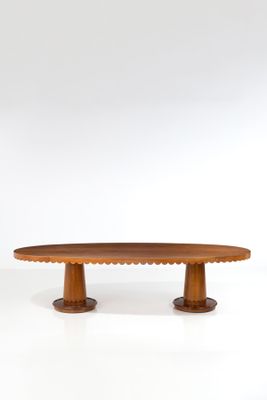 une table ovale en bois aux bords festonnés, sur fond blanc