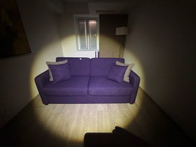 a purple couch sitting in the middle of a dark room