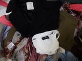 un tas de vêtements et un sac posés sur un lit