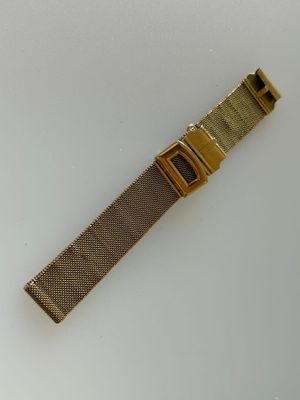 gros plan d'une montre en or sur une surface blanche