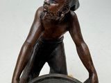 a statue of a man holding a bowl on top of a table