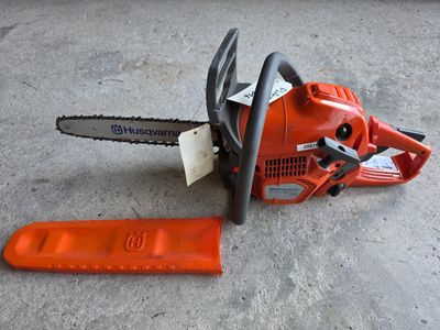 a chainsaw sitting on the ground next to a piece of paper