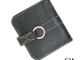 Le portefeuille en cuir noir est orné d'une boucle dorée sur le devant.