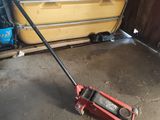 un cric rouge posé par terre dans un garage